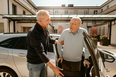 Rotkreuz-Fahrer unterstützt den Fahrgast mit dem Rollator