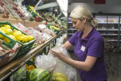 Frau füllt Regale in Laden auf