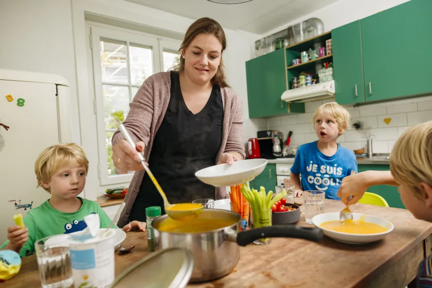 Eine Mutter sitzt mit ihren zwei Kindern am Mittagstisch